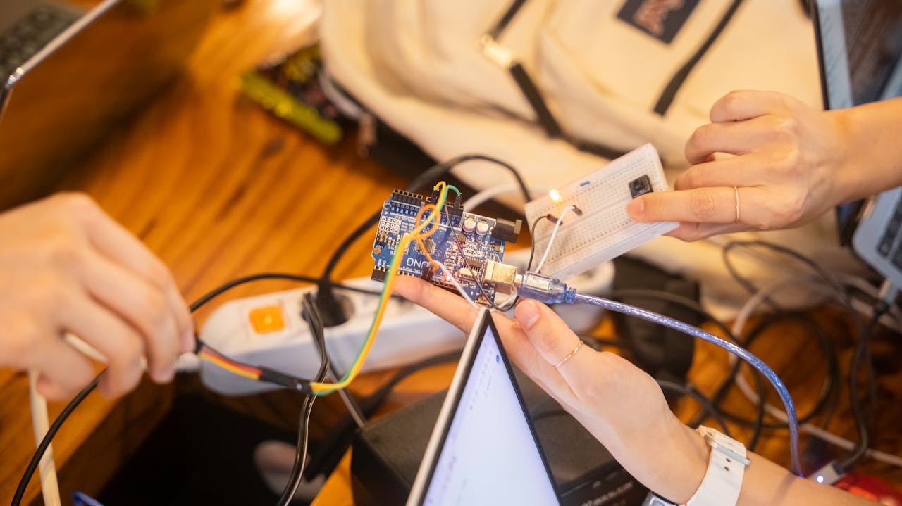A detailed view of a team collaborating on an Arduino project featuring wiring and a breadboard.